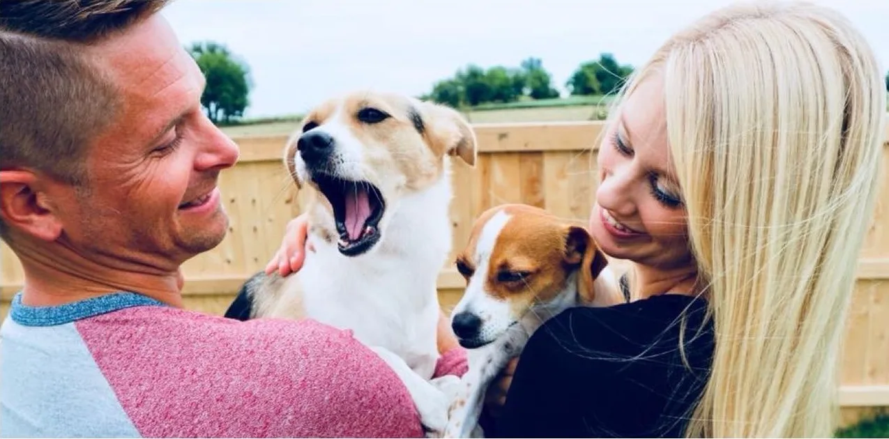 Loren and Ashley each holding one of their dogs in the backyard